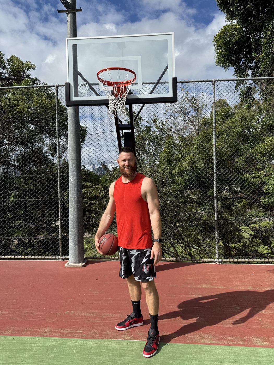 Aron Baynes smiling on an outdoor basketball court, holding a ball