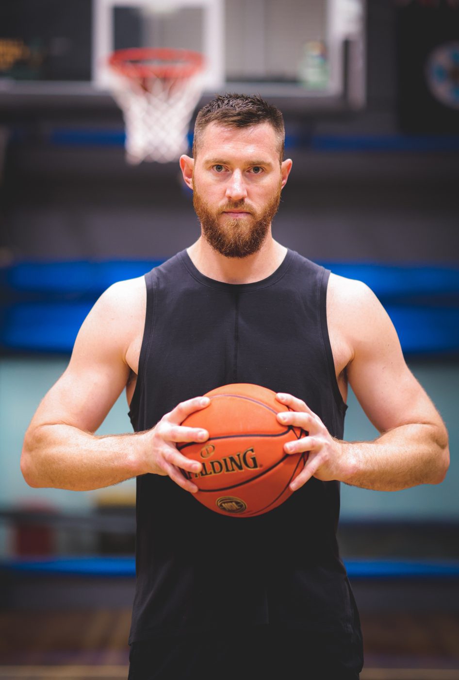 Aron Baynes holding a basketball in a gym, looking straight at the camera